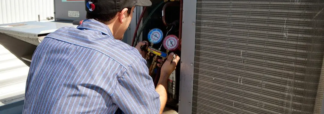 HVAC technician servicing a condenser unit in Pierre